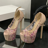 Pair of high-heeled shoes with floral design on a reflective surface.